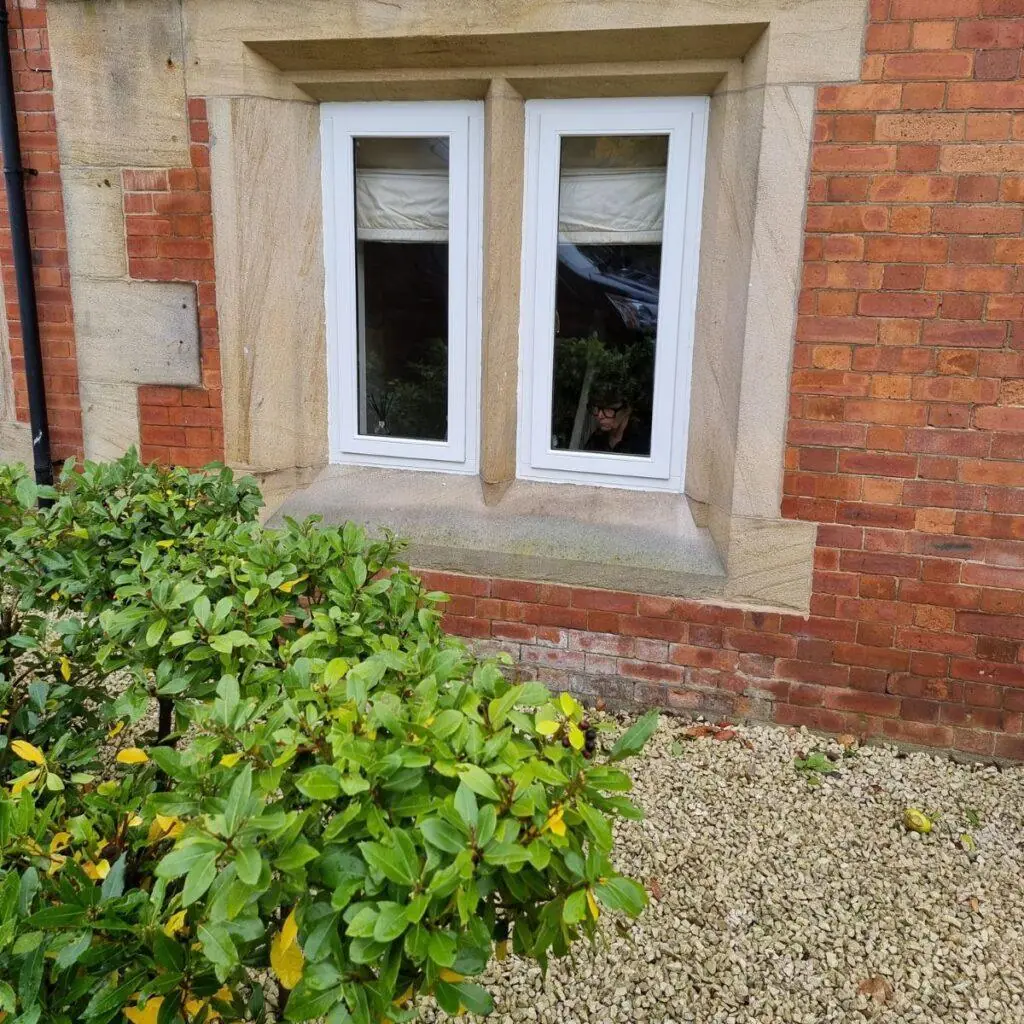 White flush casement window in a red brick and sandstone surround